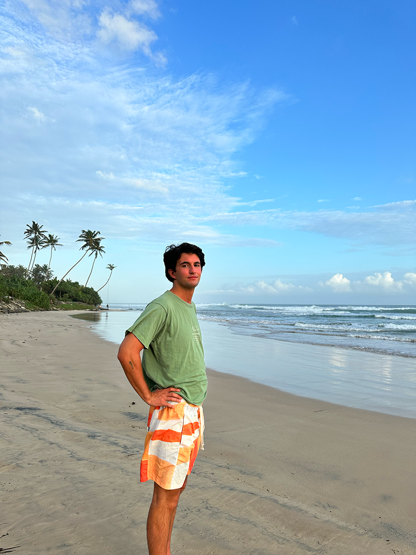 Chico con camiseta verde en una playa con palmeras de Sri Lanka