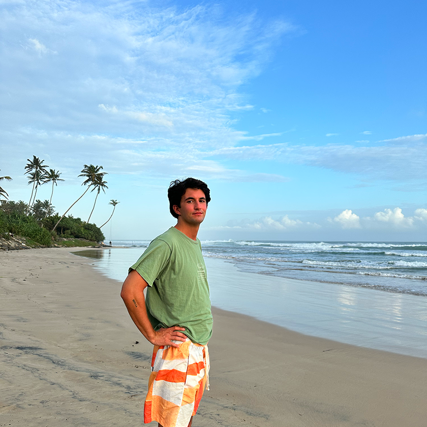 Chico con camiseta verde en una playa con palmeras de Sri Lanka
