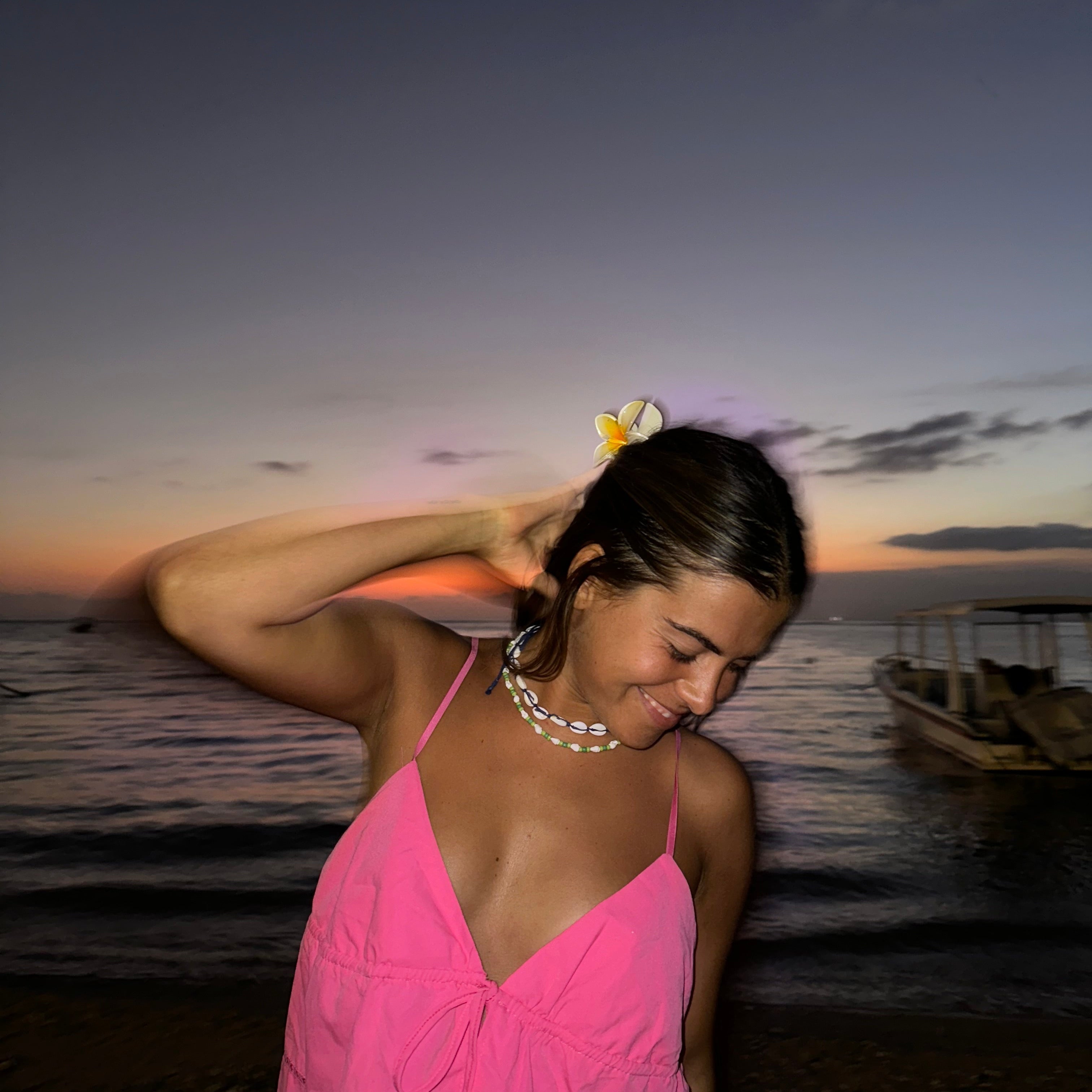Chica con vestido rosa y flor en el pelo en una playa de Tailandia al atardecer