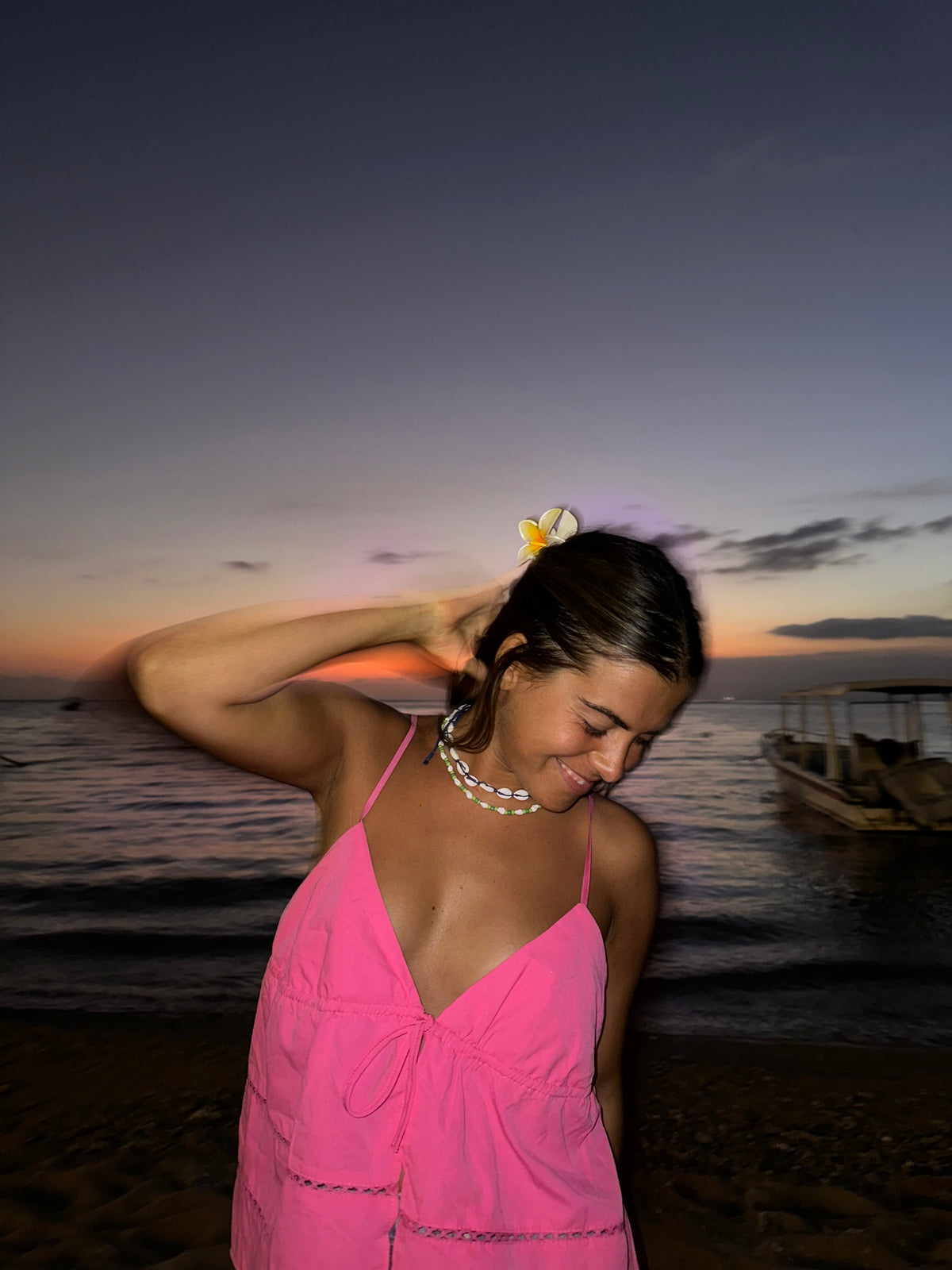 Chica con vestido rosa y flor en el pelo en una playa de Tailandia al atardecer
