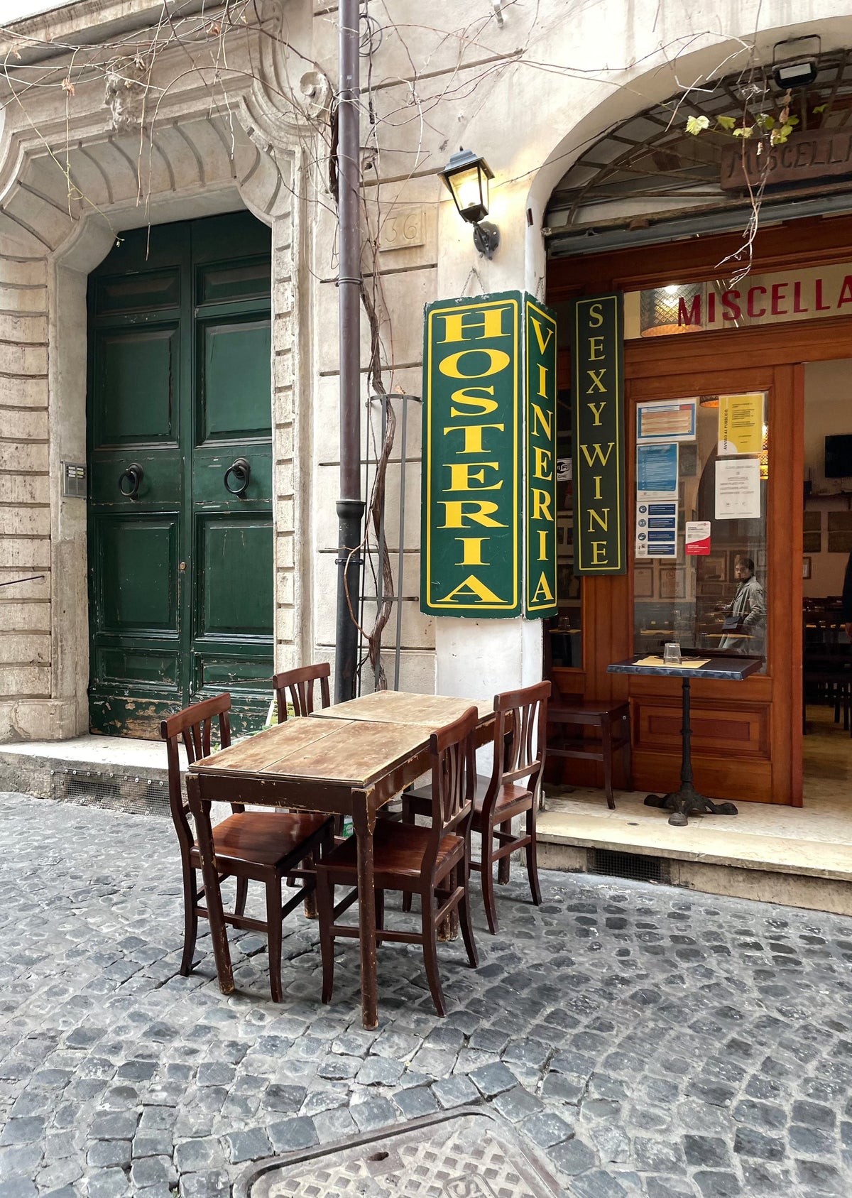 Mesa de madera en la terraza de una hostería, sobre una calle adoquinada de Roma